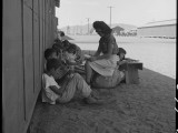 1 July 1942. Manzanar Relocation Center, Manzanar, California. An elementary school with voluntary evacuee attendance has been established with volunteer evacuee teachers, most of whom are college graduates. No school equipment is as yet obtainable and available tables and benches are used. However, classes are often held in the shade of the barrack building at this War Relocation Authority center. National Archives, 537966.