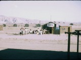 The line for a matinee at one of the camp’s two movie theaters. The blue sign to the right of the door announces the film How Green Was My Valley.