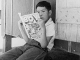1 July 1942. Manzanar Relocation Center, Manzanar, California. Evacuee boy at this War Relocation Authority center reading the Funnies. National Archives, 538076. 