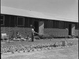 1 July 1942. Manzanar Relocation Center, Manzanar, California. A barrack home at this War Relocation Authority center for evacuees of Japanese ancestry has been beautified by flowers, lawn and a small rock garden. National Archives, 538156.
