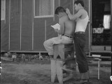  2 July 1942. Manzanar Relocation Center, Manzanar, California. Common sight during the long summer evenings after the day's work is done. As yet, there are no barbershops. National Archives, 538084.