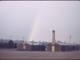 A rainbow appears to end at a latrine and laundry building.